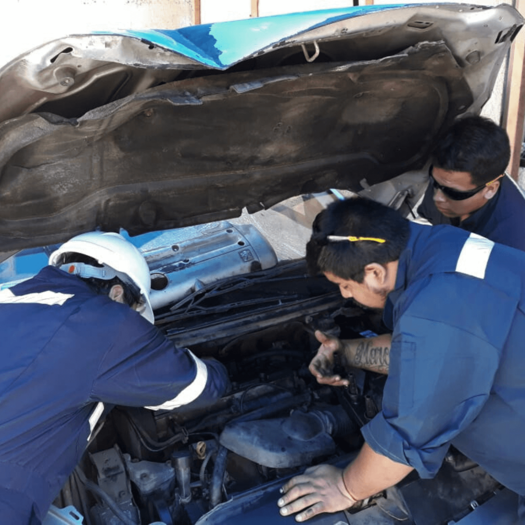 tres estudiantes de dvc haciendo mecánica en un auto en el curso de mecánica básica